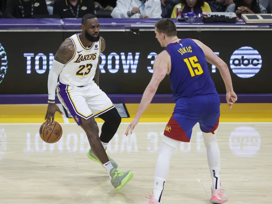 Los Angeles Lakers forward LeBron James (23) dribbles the ball as Denver Nuggets center Nikola Jokic (15) defends during the second half of an NBA basketball game Saturday, March 2, 2024, in Los Angeles.Yannick Peterhans/AP